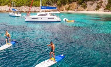 Catamaran Anchoring and People Stand Up Paddling Corfu Island